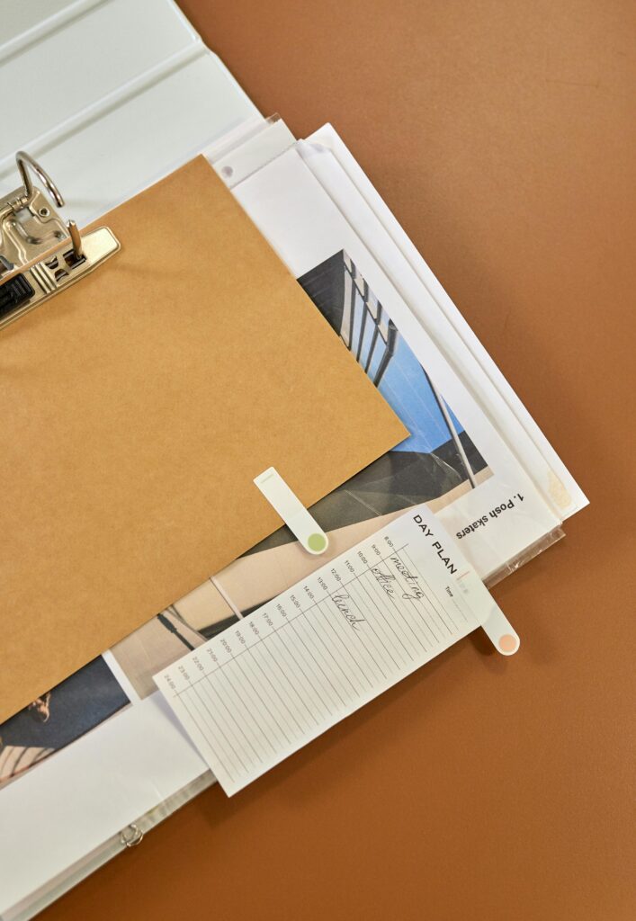 High-angle view of a clipboard, papers, and planner on a desk, promoting productivity and organization.